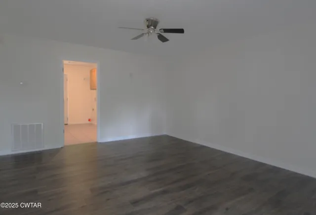 an empty room with wooden floor and fan