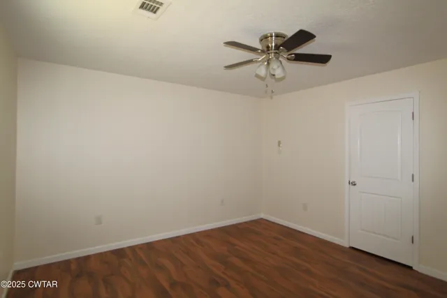 a view of a room with wooden floor and ceiling fan