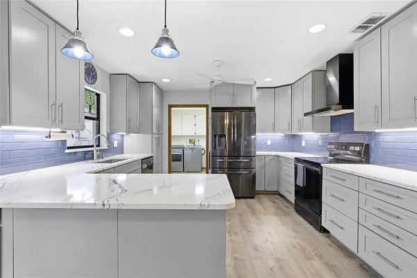 a kitchen with stainless steel appliances kitchen island granite countertop a sink refrigerator and cabinets