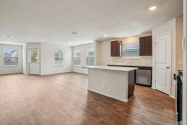 a large white kitchen with granite countertop a sink and a stove top oven