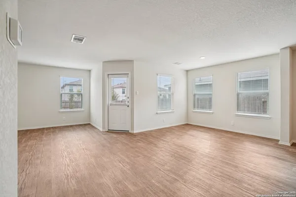 a view of an empty room with window and wooden floor