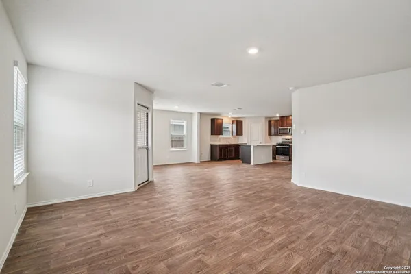 a view of empty room with kitchen and window