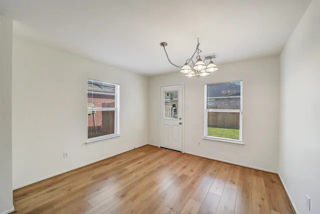 an empty room with wooden floor cabinet and windows
