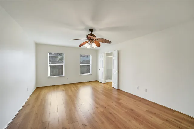 a view of empty room with wooden floor and fan