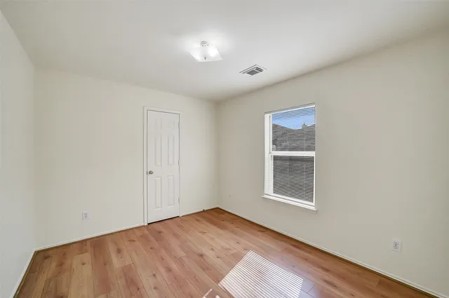 a view of an empty room with a window and wooden floor