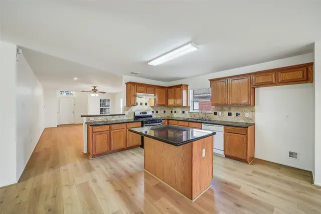 a kitchen with stainless steel appliances granite countertop a sink a stove a refrigerator cabinets and living room view
