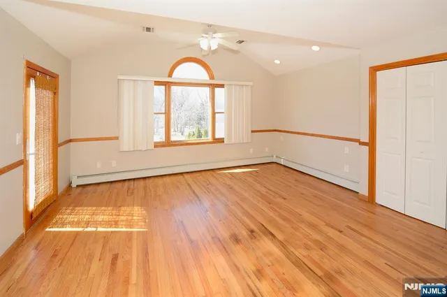 a view of an empty room with a window and wooden floor