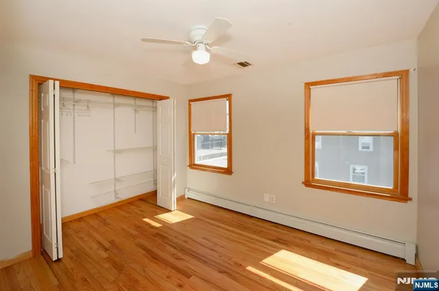 an empty room with wooden floor fan and windows