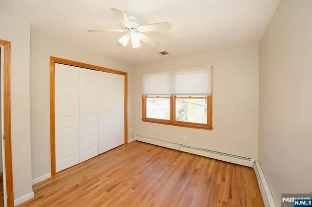 an empty room with wooden floor fan and windows