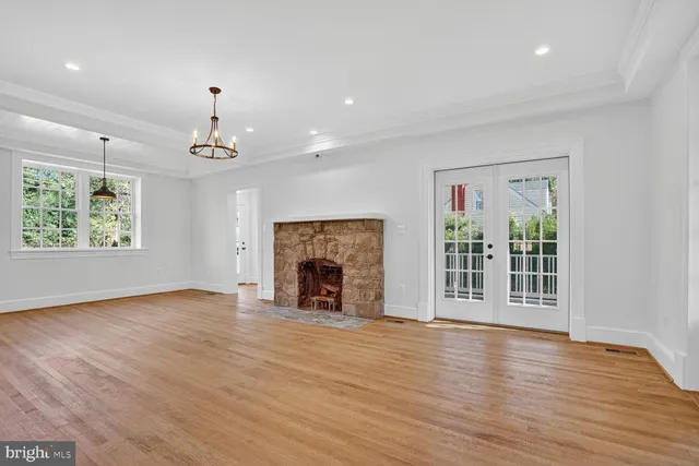 an empty room with windows fireplace and wooden floor