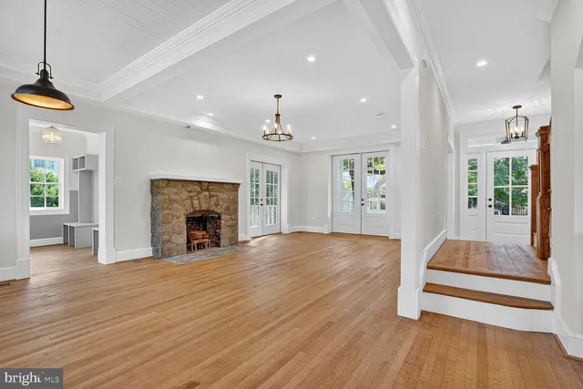 an empty room with wooden floor fireplace and windows