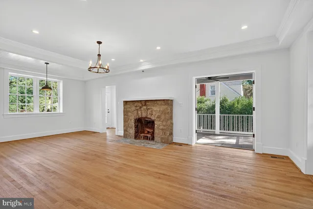 an empty room with wooden floor fireplace and windows