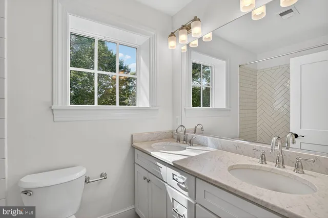 a bathroom with a granite countertop sink a toilet and a mirror