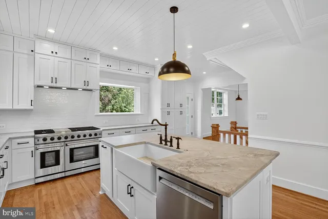 a kitchen with stainless steel appliances granite countertop a sink a stove and a wooden floors