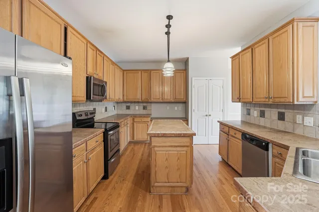 a kitchen with stainless steel appliances granite countertop a stove a sink dishwasher a refrigerator white cabinets and wooden floor