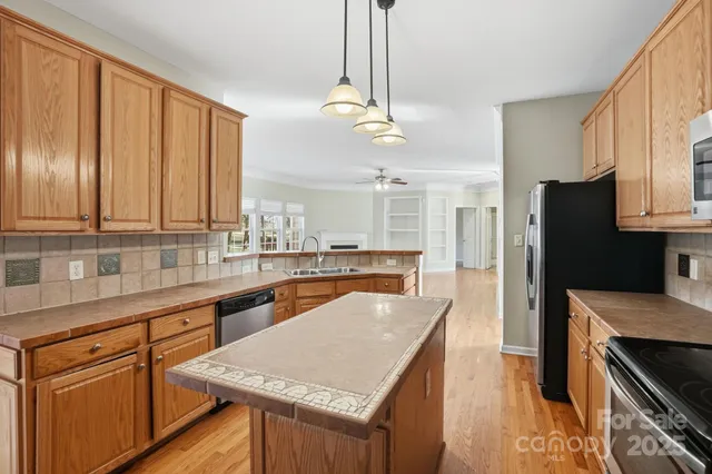 a kitchen with stainless steel appliances granite countertop wooden cabinets a refrigerator and a sink