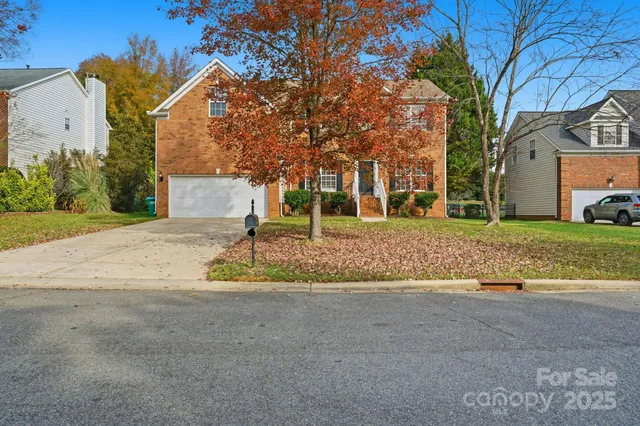 a view of a house with a yard and large tree