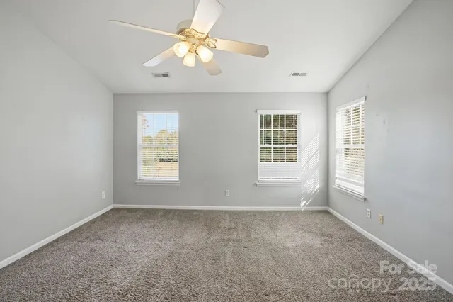 an empty room with windows and chandelier fan