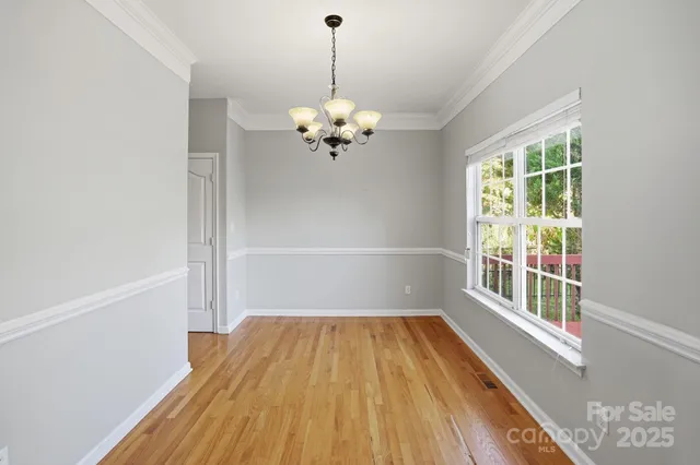 a view of a room with wooden floor chandelier and a window