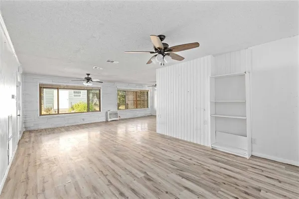 an empty room with wooden floor chandelier and windows