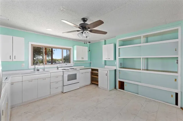 a large white kitchen with stainless steel appliances granite countertop a sink and cabinets