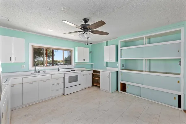 a large white kitchen with stainless steel appliances granite countertop a sink and cabinets