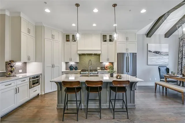 a kitchen with stainless steel appliances a dining table chairs stove sink and refrigerator