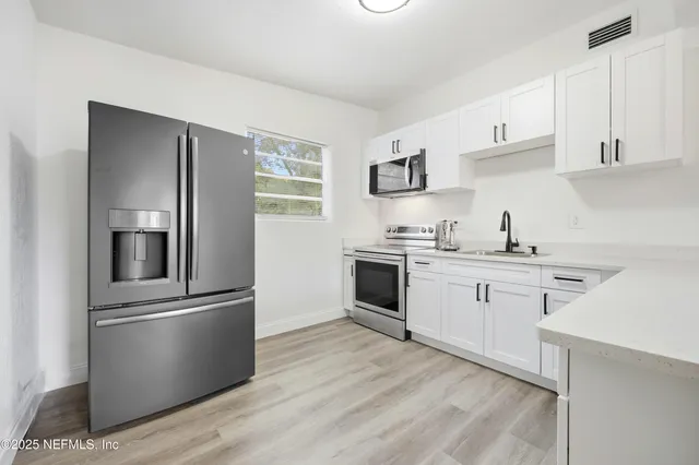 a kitchen with cabinets stainless steel appliances and wooden floor