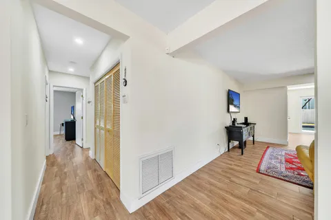 a view of a hallway with wooden floor and closet area