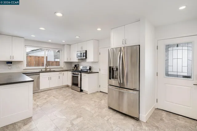 a kitchen with granite countertop white cabinets and stainless steel appliances