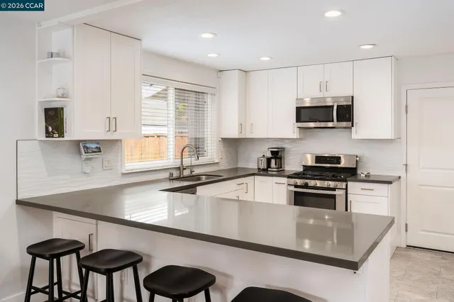 a kitchen with stainless steel appliances granite countertop a sink a stove a table and chairs in it