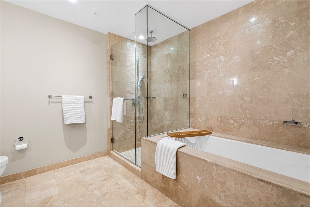 1 Franklin Street, Unit 1408 Boston, MA 02110 - Photo 18 of 37 a spacious bathroom with a granite countertop sink a toilet a mirror and shower