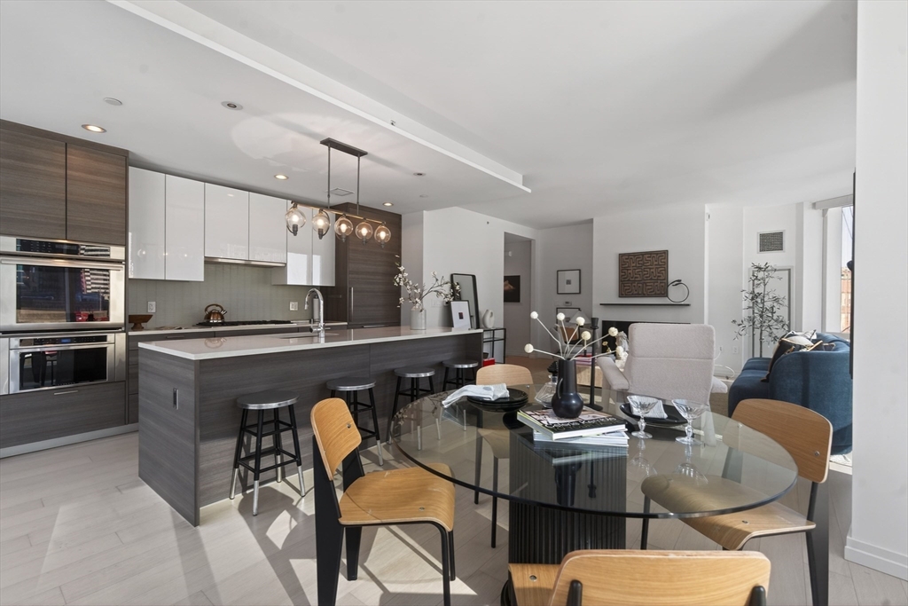 1 Franklin Street, Unit 1408 Boston, MA 02110 - Photo 5 of 37 a kitchen with stainless steel appliances granite countertop a stove a sink dishwasher a dining table and chairs with wooden floor
