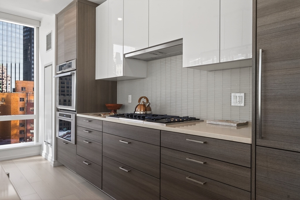 1 Franklin Street, Unit 1408 Boston, MA 02110 - Photo 9 of 37 a kitchen with granite countertop cabinets and white stainless steel appliances