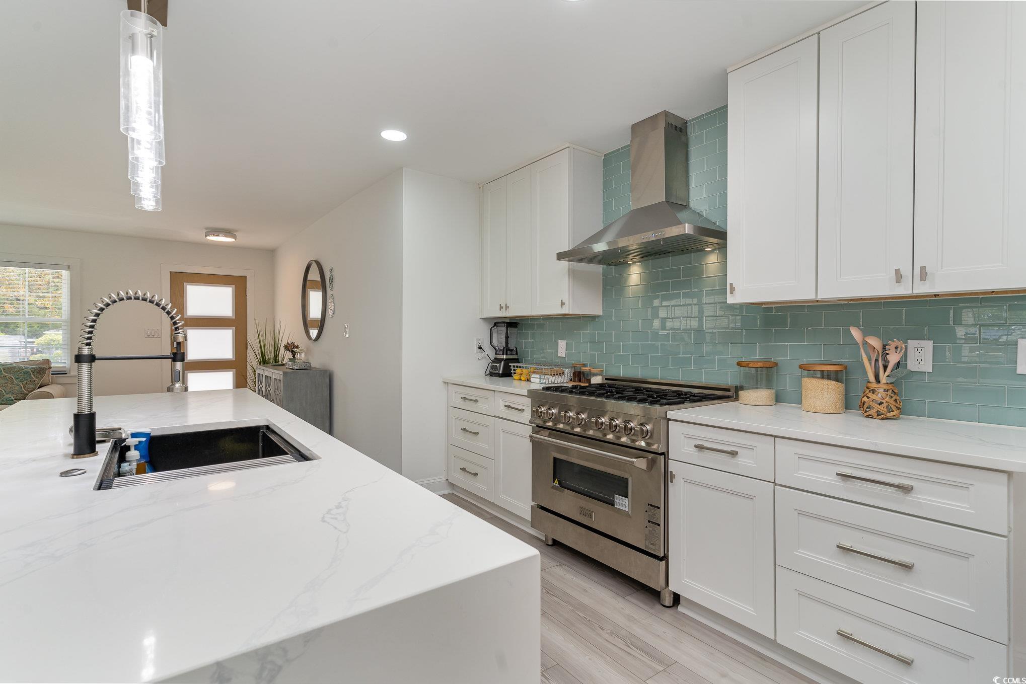 5811 Sumter Drive Myrtle Beach, SC 29577 - Photo 11 of 39 Kitchen featuring stainless steel stove, light stone countertops, wall chimney exhaust hood, hanging light fixtures, and recessed lighting