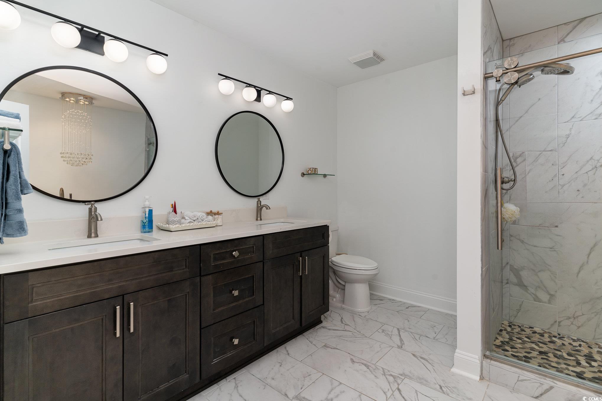 5811 Sumter Drive Myrtle Beach, SC 29577 - Photo 26 of 39 Full bathroom with double vanity, a marble finish shower, and light marble finish floors