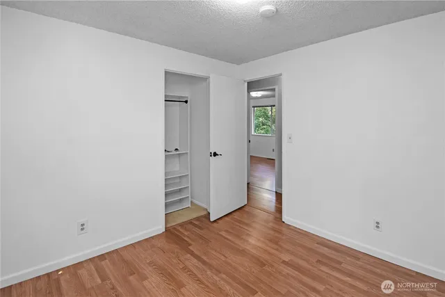 a view of an empty room with wooden floor and closet