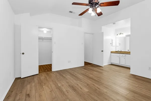 a view of empty room with wooden floor and ceiling fan