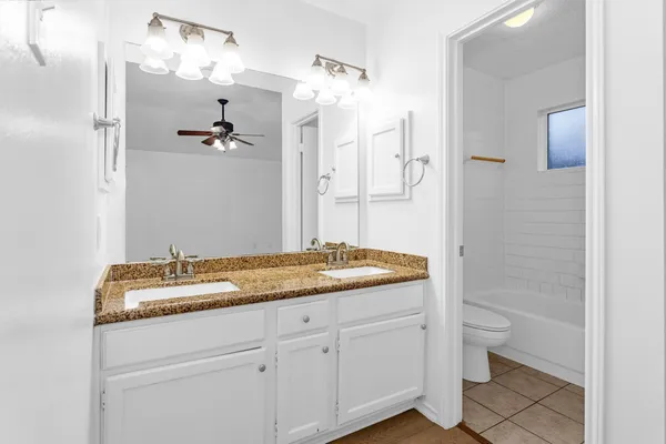 a bathroom with a granite countertop sink a toilet and a mirror
