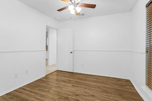 an empty room with wooden floor and fan