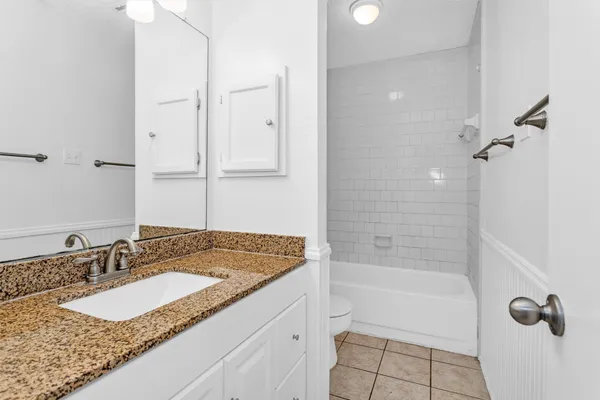 a bathroom with a granite countertop sink a mirror and a bathtub