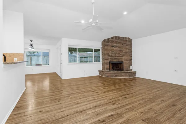 a view of an empty room with wooden floor and a fireplace