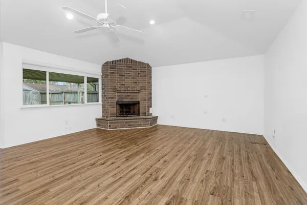 an empty room with wooden floor fireplace and windows