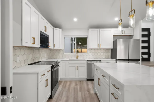 a kitchen with stainless steel appliances a stove a refrigerator and white cabinets with wooden floors