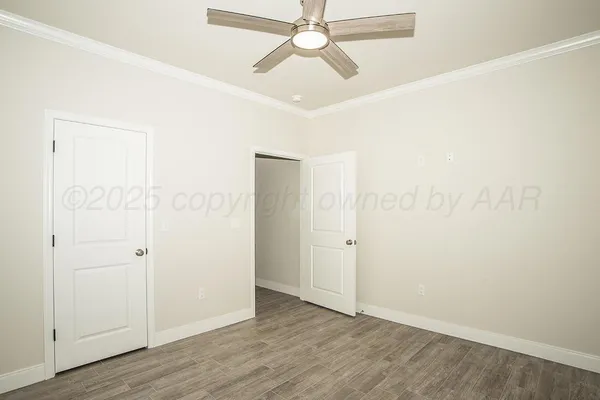 an empty room with wooden floor and ceiling fan