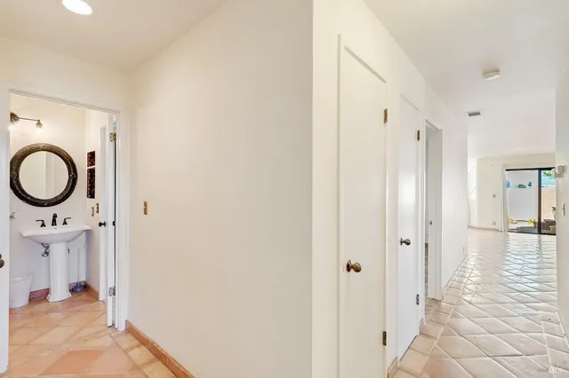 a view of a hallway with wooden floor and a bathroom