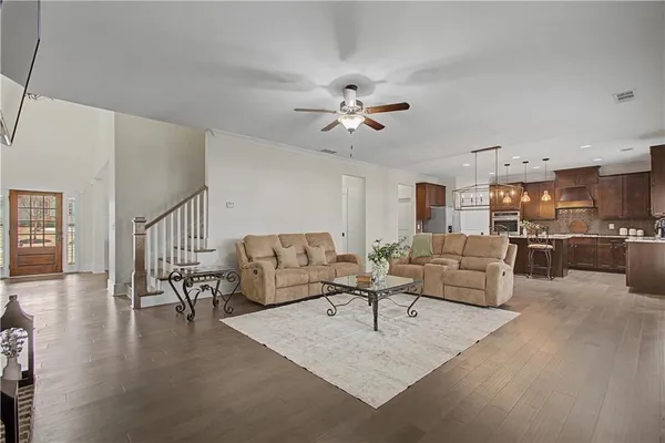 a living room with furniture dining table a lamp and a kitchen view