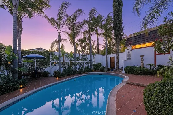 a backyard of a house with table and chairs under an umbrella