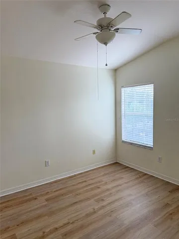 a view of an empty room with a window and wooden floor
