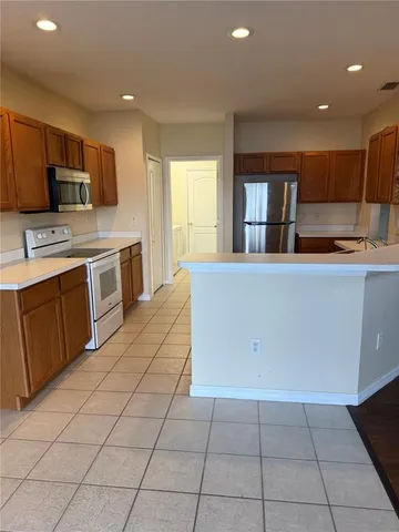 a large kitchen with stainless steel appliances a stove a sink a microwave and cabinets